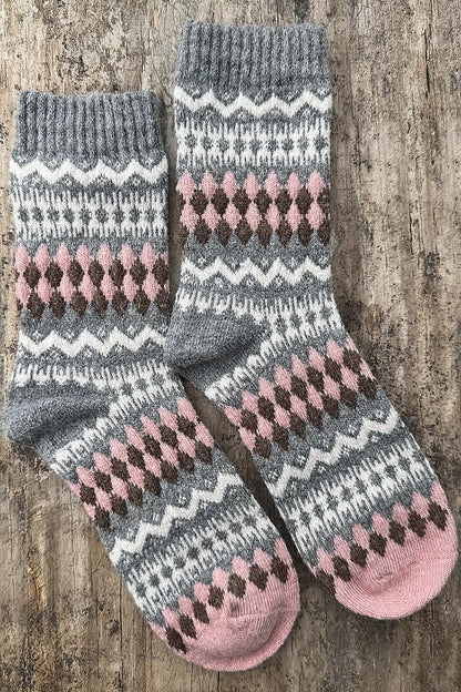 Pair of gray and pink patterned socks on a wooden surface