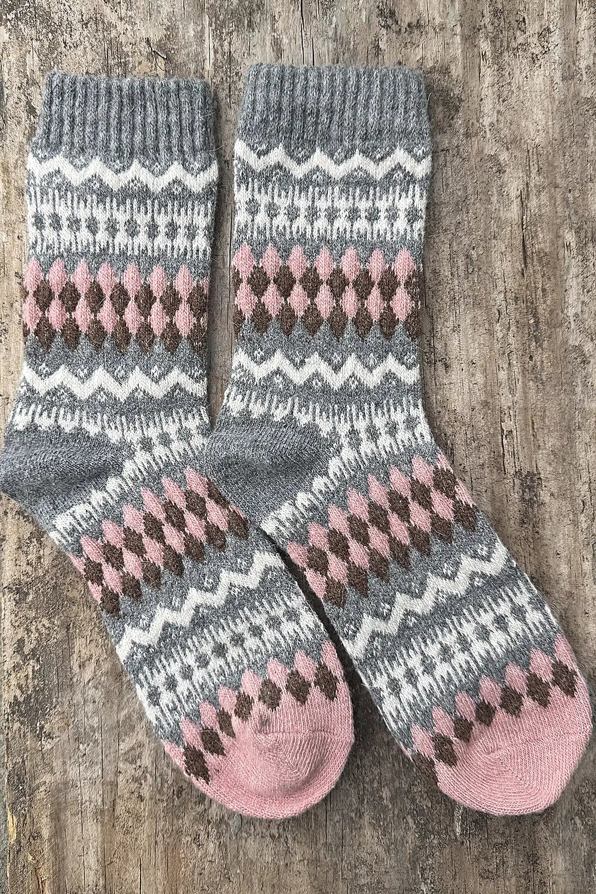 Pair of patterned socks with pink and gray design on a wooden surface