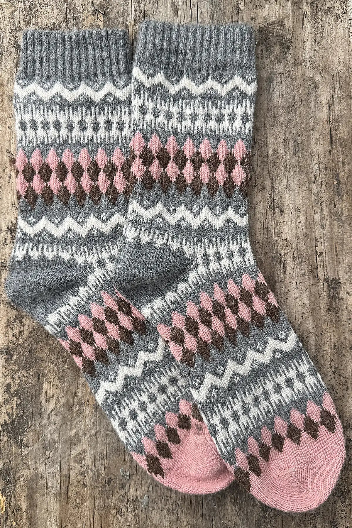 Pair of gray and pink patterned socks on a wooden surface