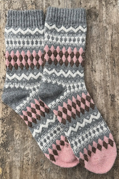 Pair of gray and pink patterned socks on a wooden surface