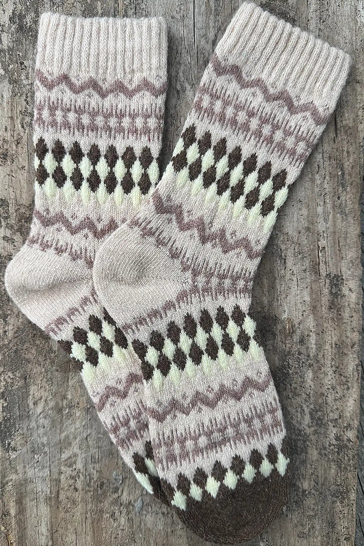 Pair of knitted socks with a pattern on a wooden surface
