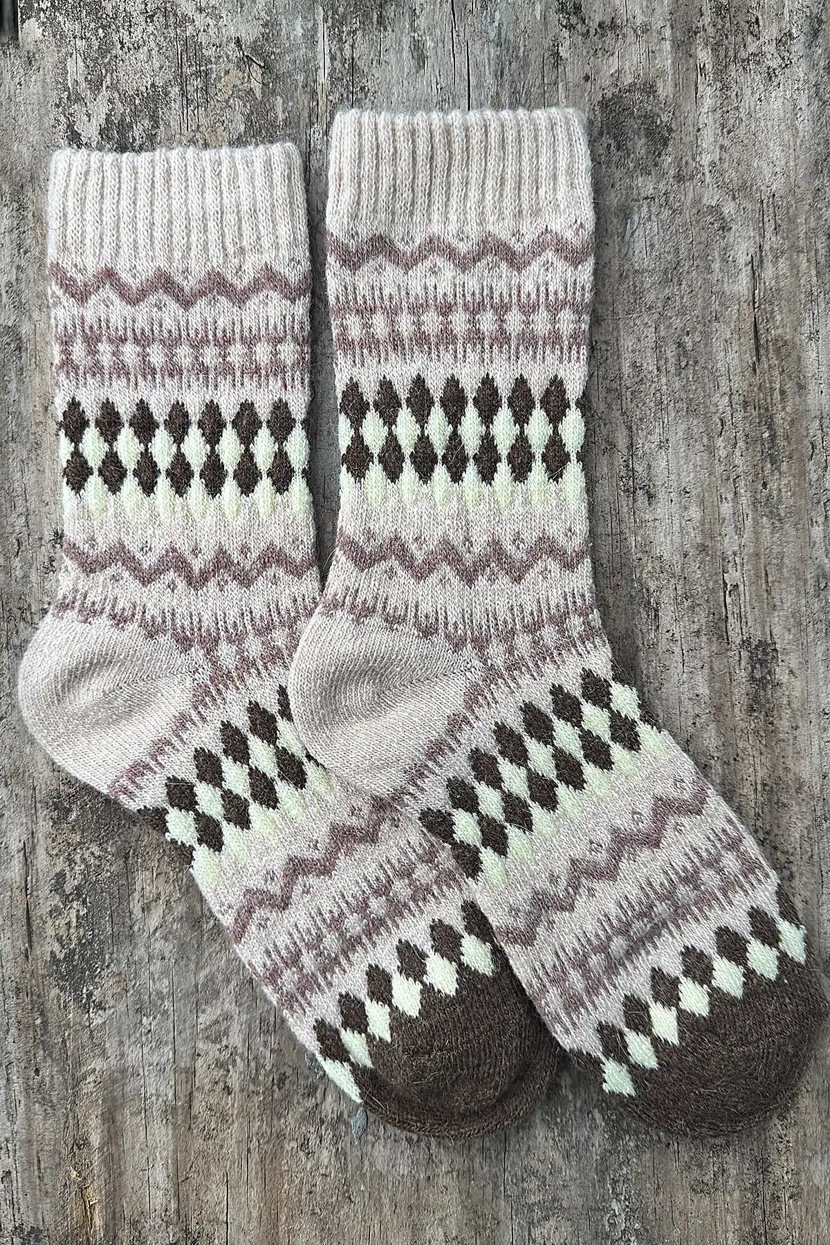 Pair of knitted socks with a pattern on a wooden surface