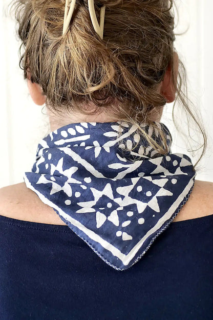 Person wearing a blue and white patterned bandana around their neck against a white background