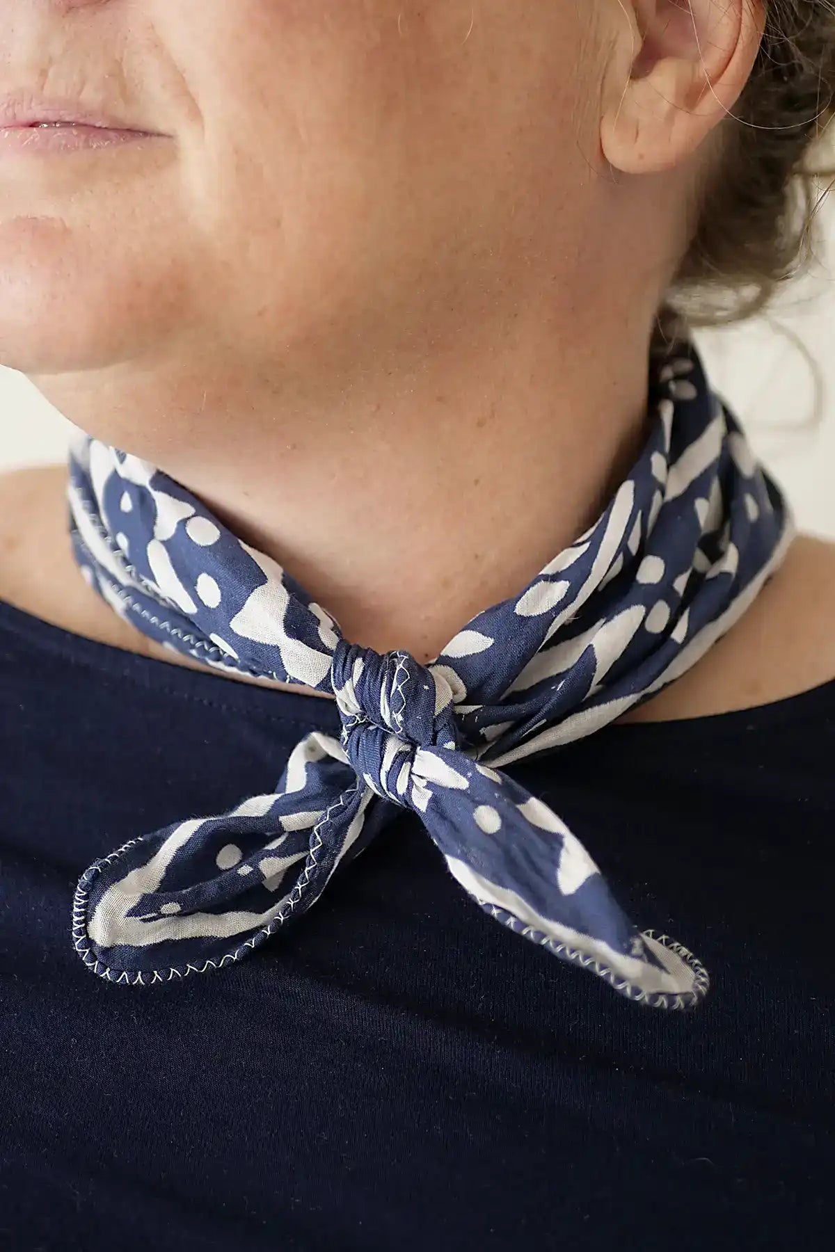 Person wearing a navy blue scarf with white patterns around their neck