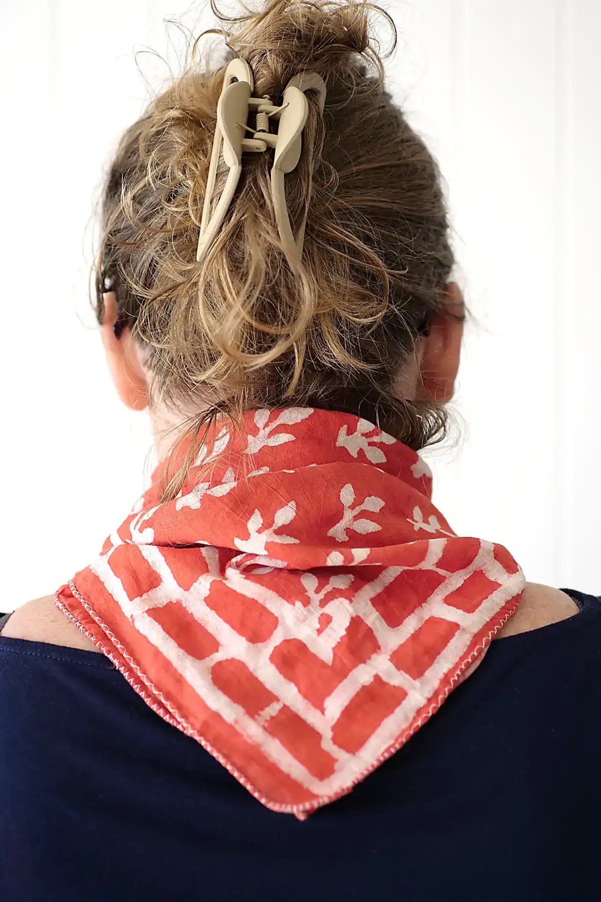 Person wearing a red and white patterned scarf on a plain background