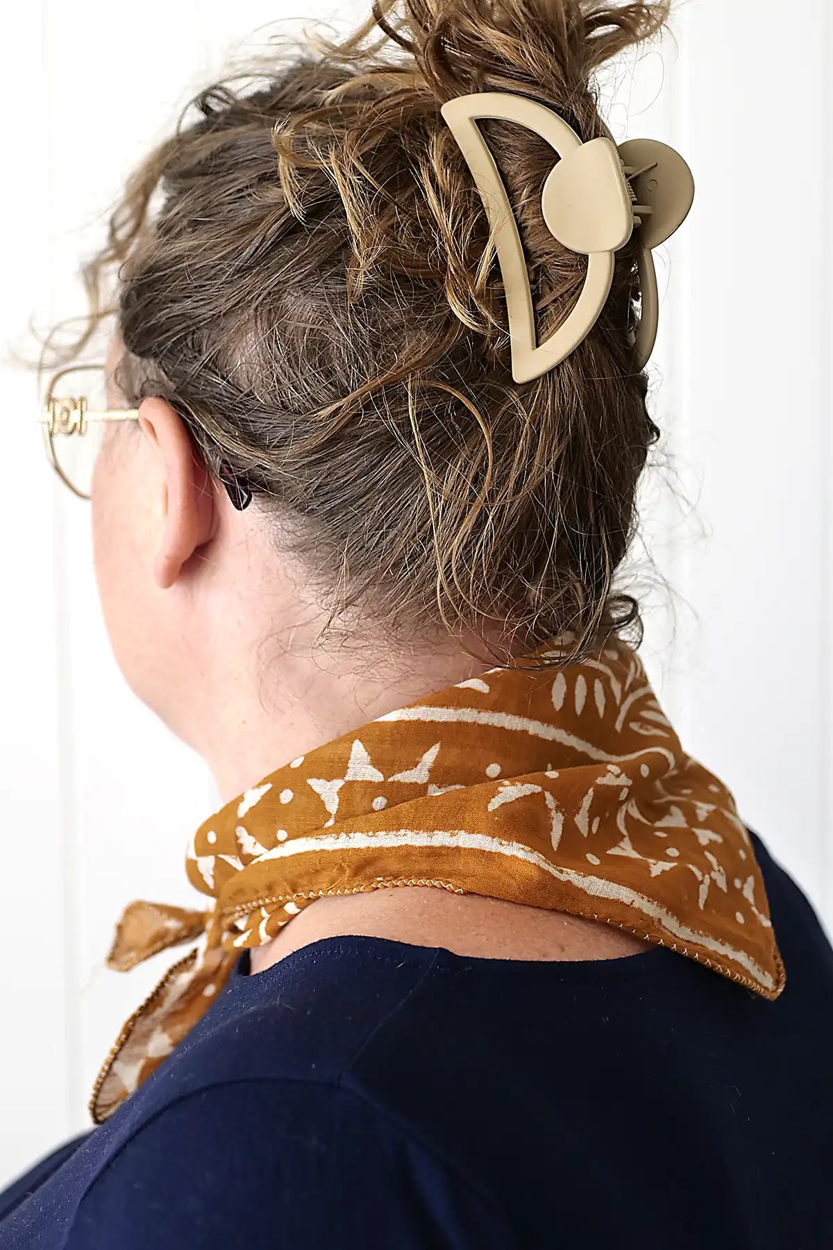 Person wearing a patterned headband and scarf with a neutral background