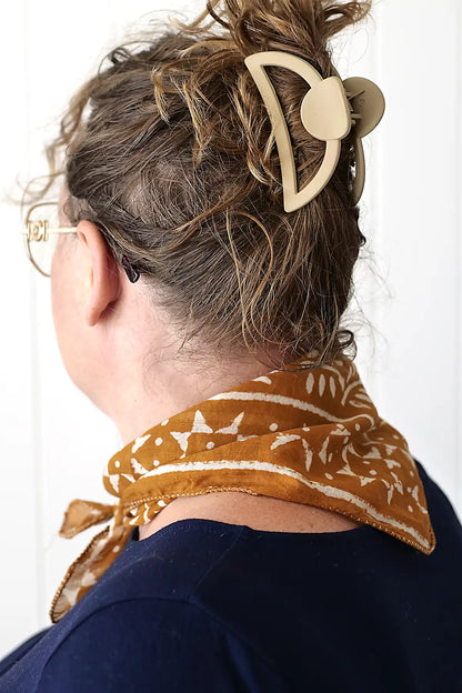 Person wearing a patterned headband and scarf with a neutral background