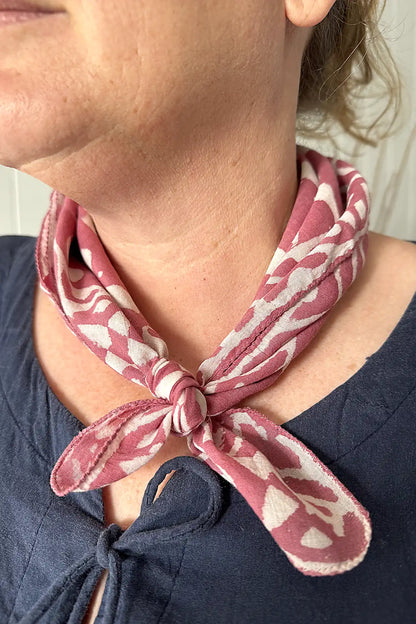 Person wearing a pink and white patterned scarf around their neck