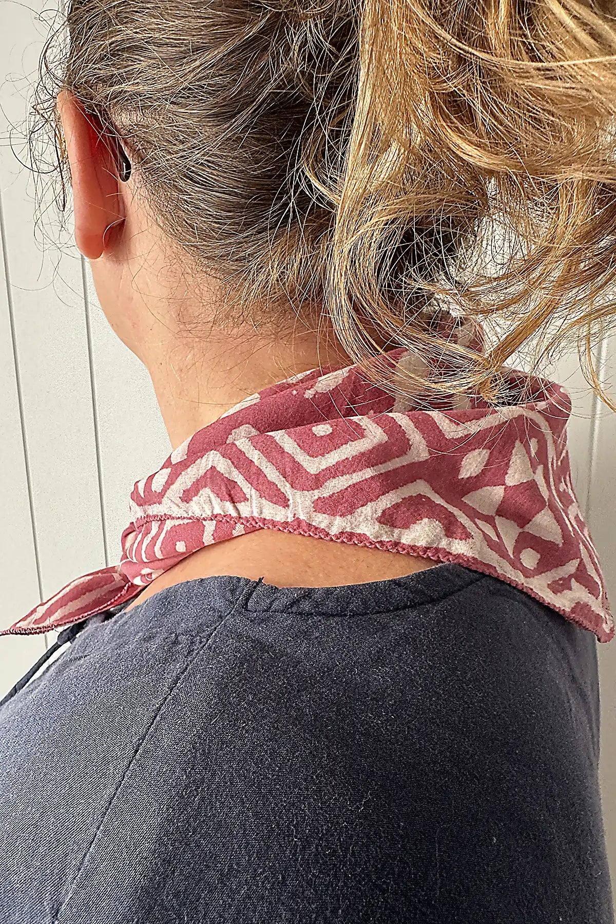 Person wearing a patterned neckerchief with a neutral background