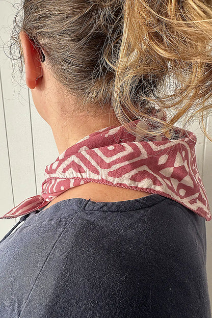 Person wearing a patterned neckerchief with a neutral background