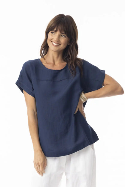 Woman wearing a Orientique Escape Linen Solid Boxy Navy Top and white pants on a white background