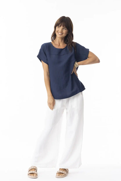 Woman wearing a Orientique Escape Linen Solid Boxy Navy Top and white pants on a white background
