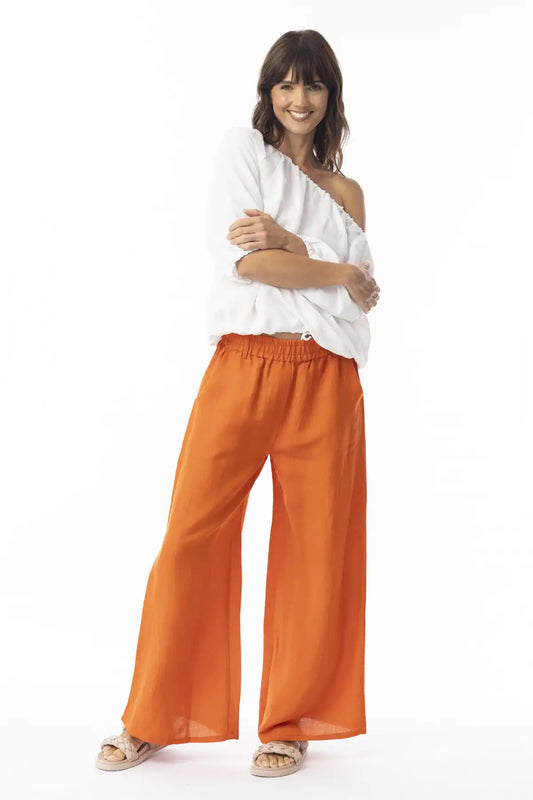 Woman wearing a white off-shoulder top and Orientique Escape Linen Wide Leg Pants in Mandarin on a white background