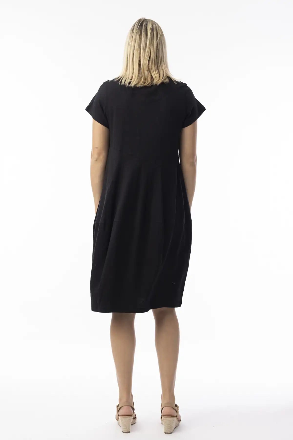 Woman wearing aOrientique Essentials Organic Cotton Bubble Dress in black from behind on a white background