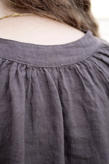 Close-up of a dark chocolate top with a neckline and part of a person's hair visible.