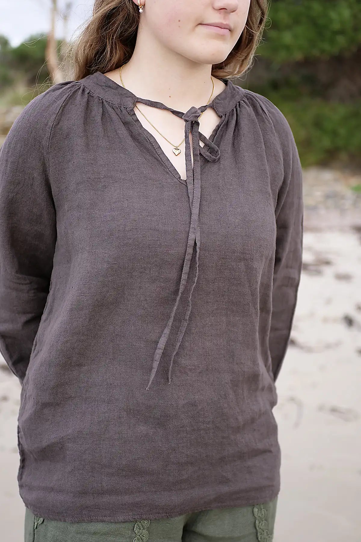 Person wearing a dark brown long-sleeve top with a lace-up front, standing outdoors.