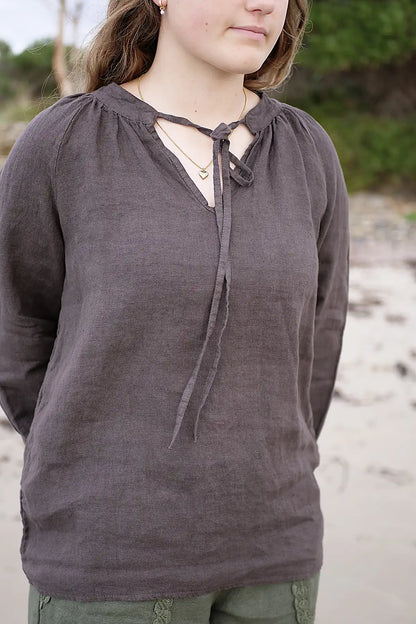 Person wearing a dark brown long-sleeve top with a lace-up front, standing outdoors.