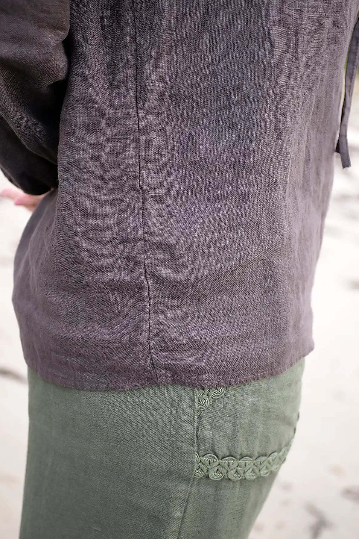 Close-up of a person wearing a dark chocolate top and green pants with lace trim.