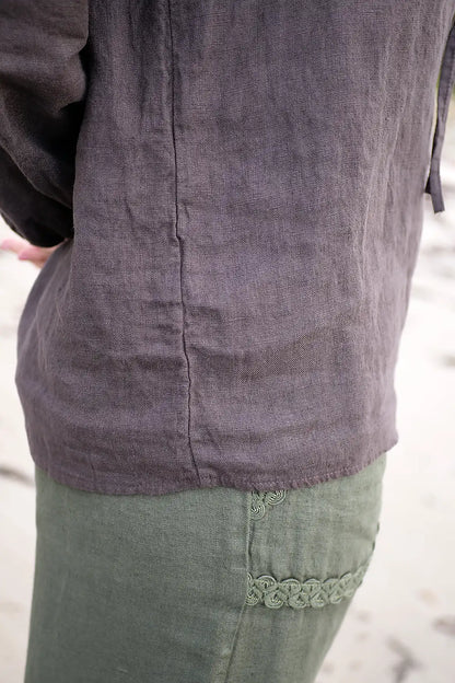 Close-up of a person wearing a dark chocolate top and green pants with lace trim.