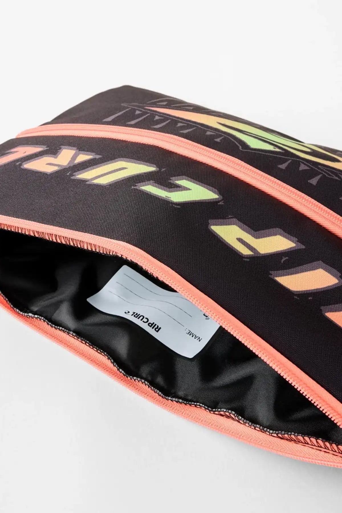 Black pencil case with bright orange zipper and Rip Curl Graphic Logo on the cover with the zipper open showing the inside of the pencil case and name area.