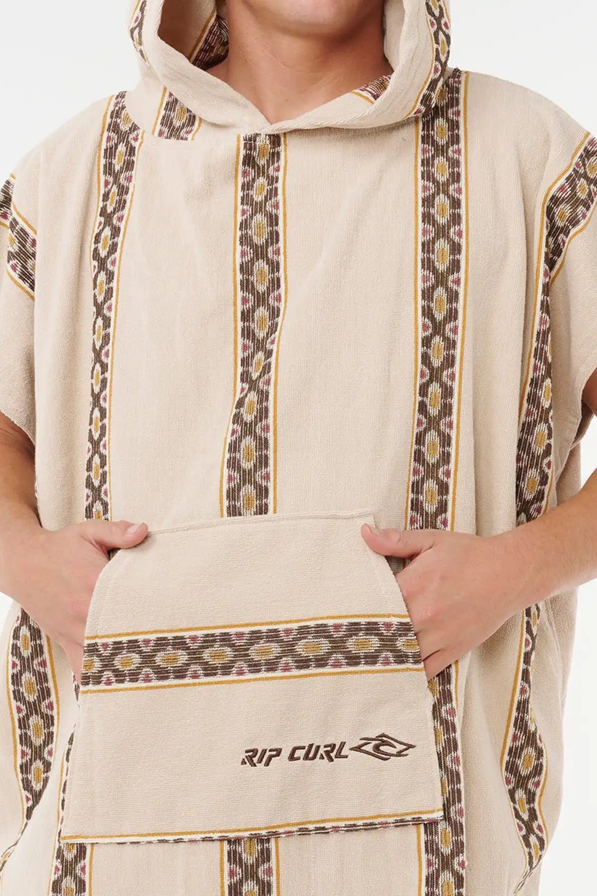 Person wearing a beige Hooded towel with patterned sleeves and 'Rip Curl' logo.