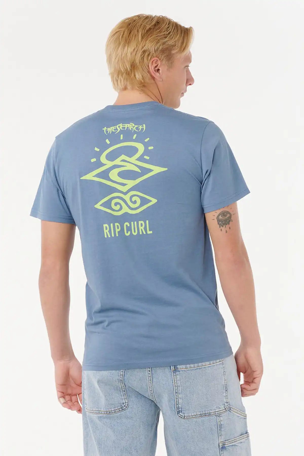 Person wearing a Rip Curl Mens Search Icon Tee in Blue Fin with a logo on the back against a white background back view