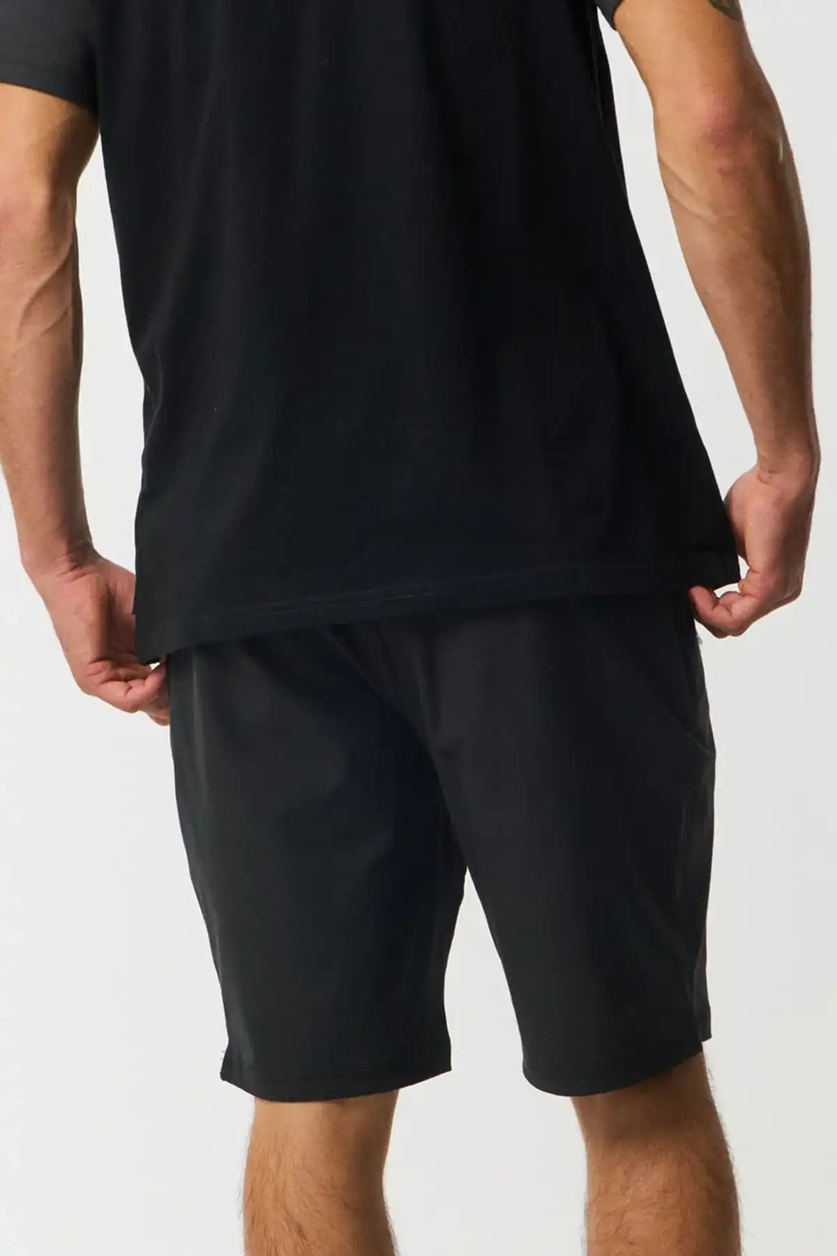 Person wearing a black t-shirt and black shorts on a white background