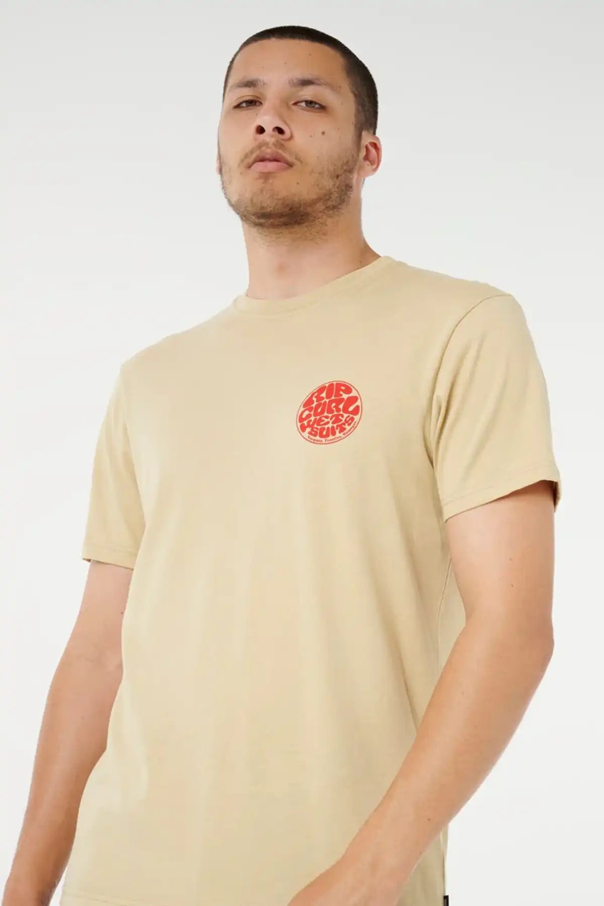 Man wearing a khaki sand t-shirt with a red Rip Curl Wettie logo on a white background