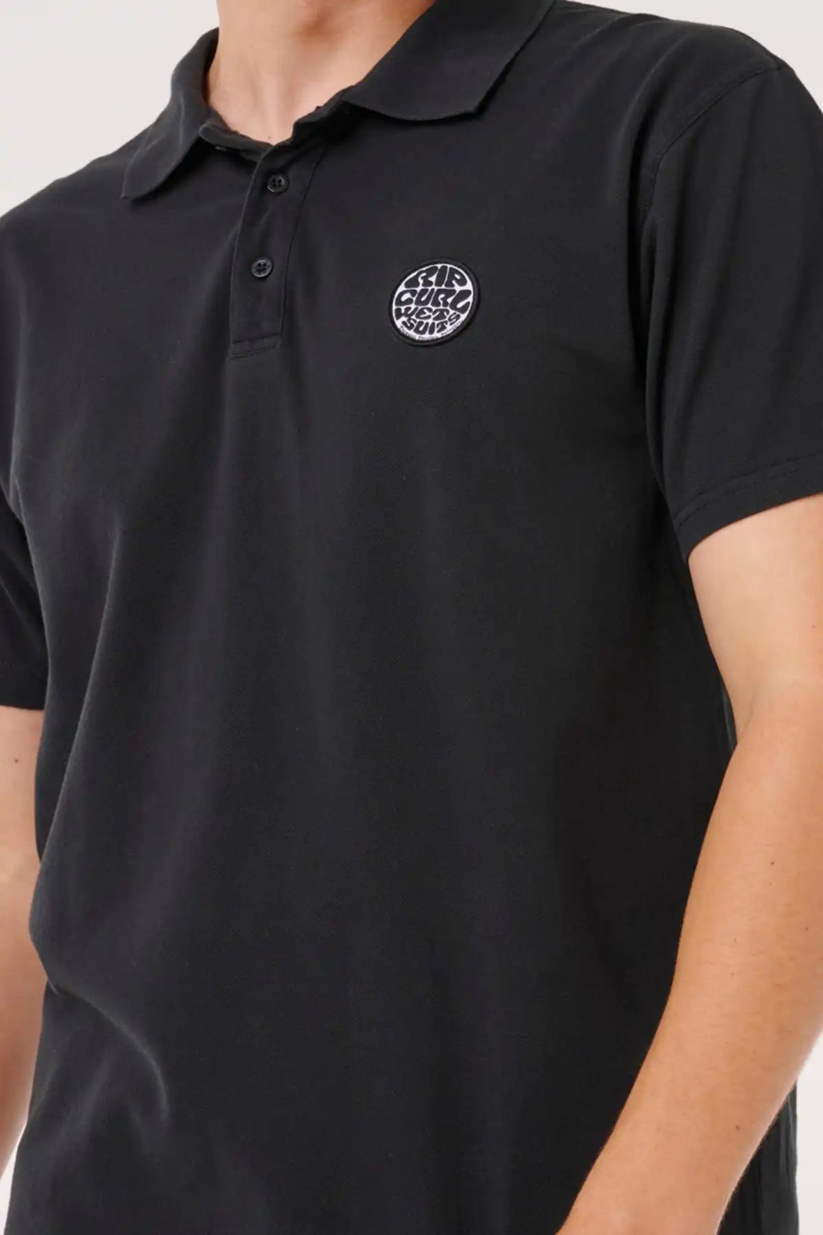 Black polo shirt with a Rip Curl logo on the chest against a neutral background