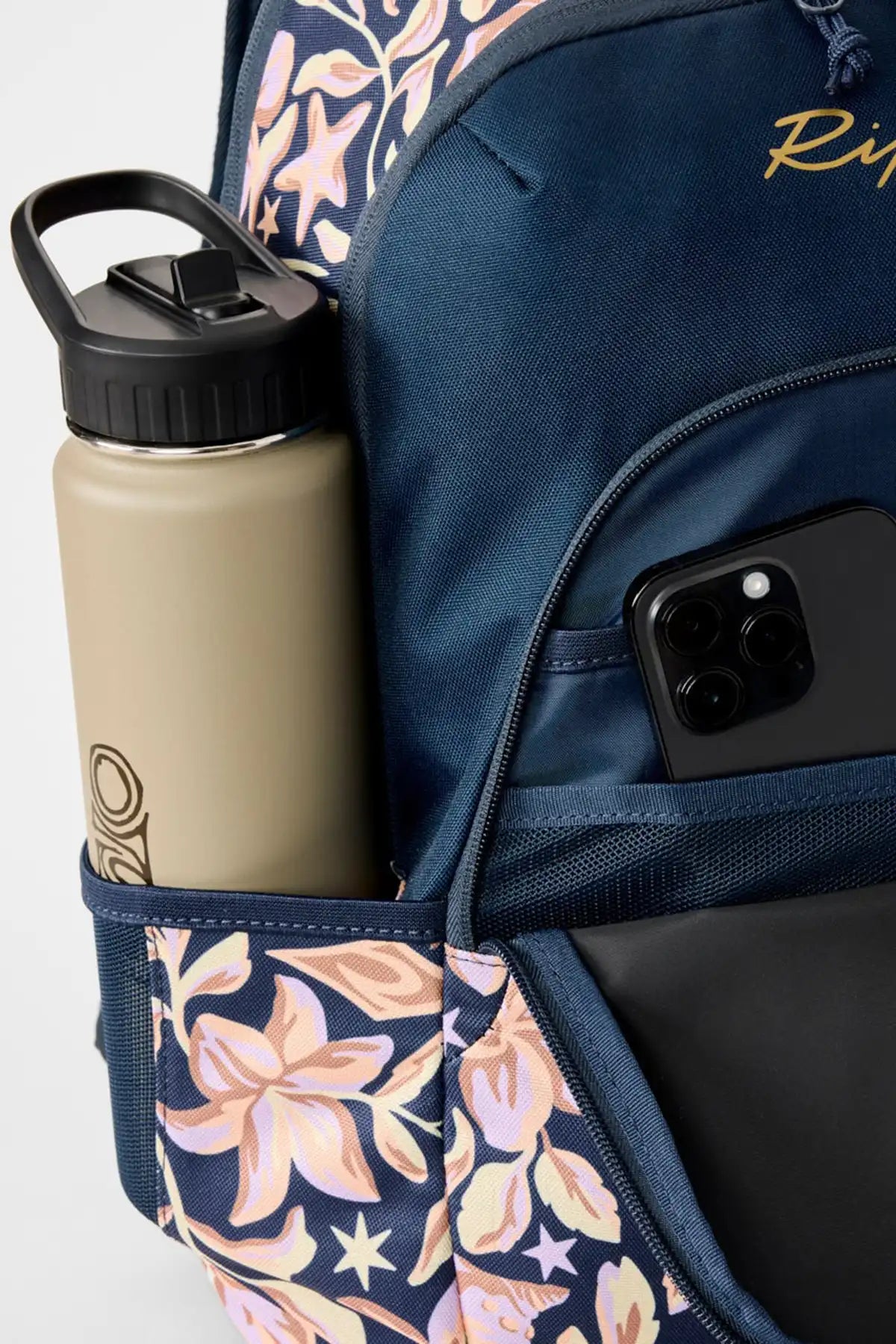 Navy backpack with floral accents, beige water bottle, and black phone inside.