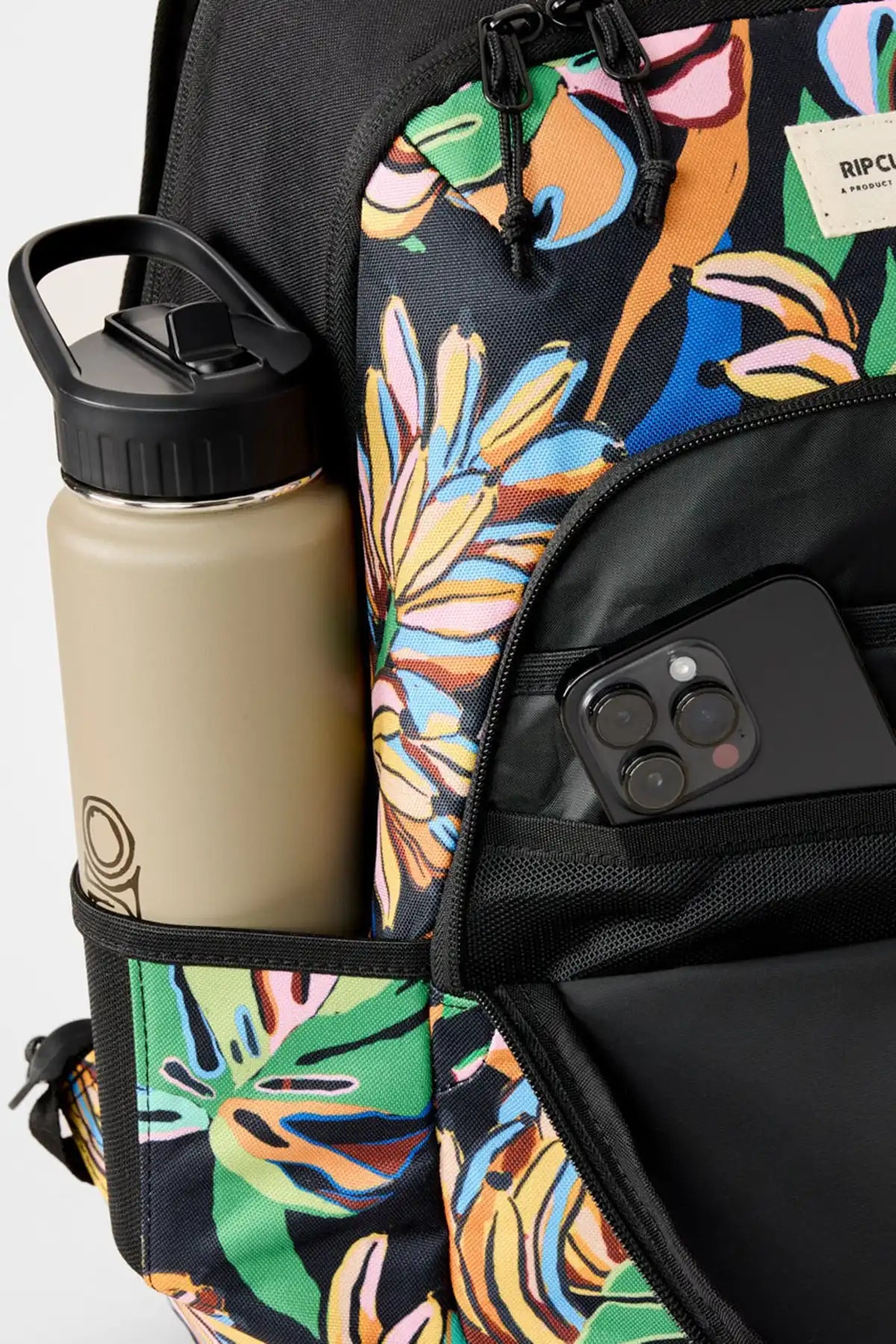 Backpack with colorful floral pattern, water bottle, and phone inside, on a light gray background.