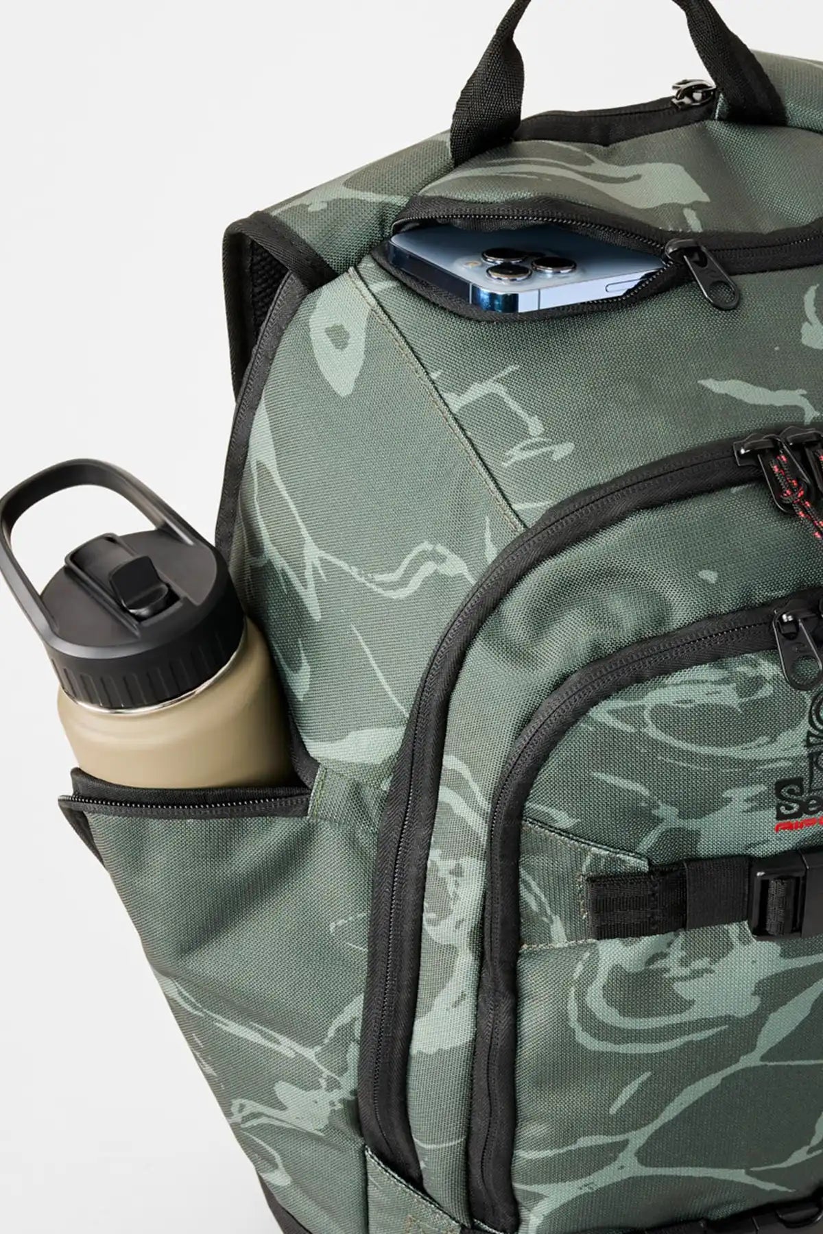 Camouflage backpack with a water bottle and phone inside on a white background