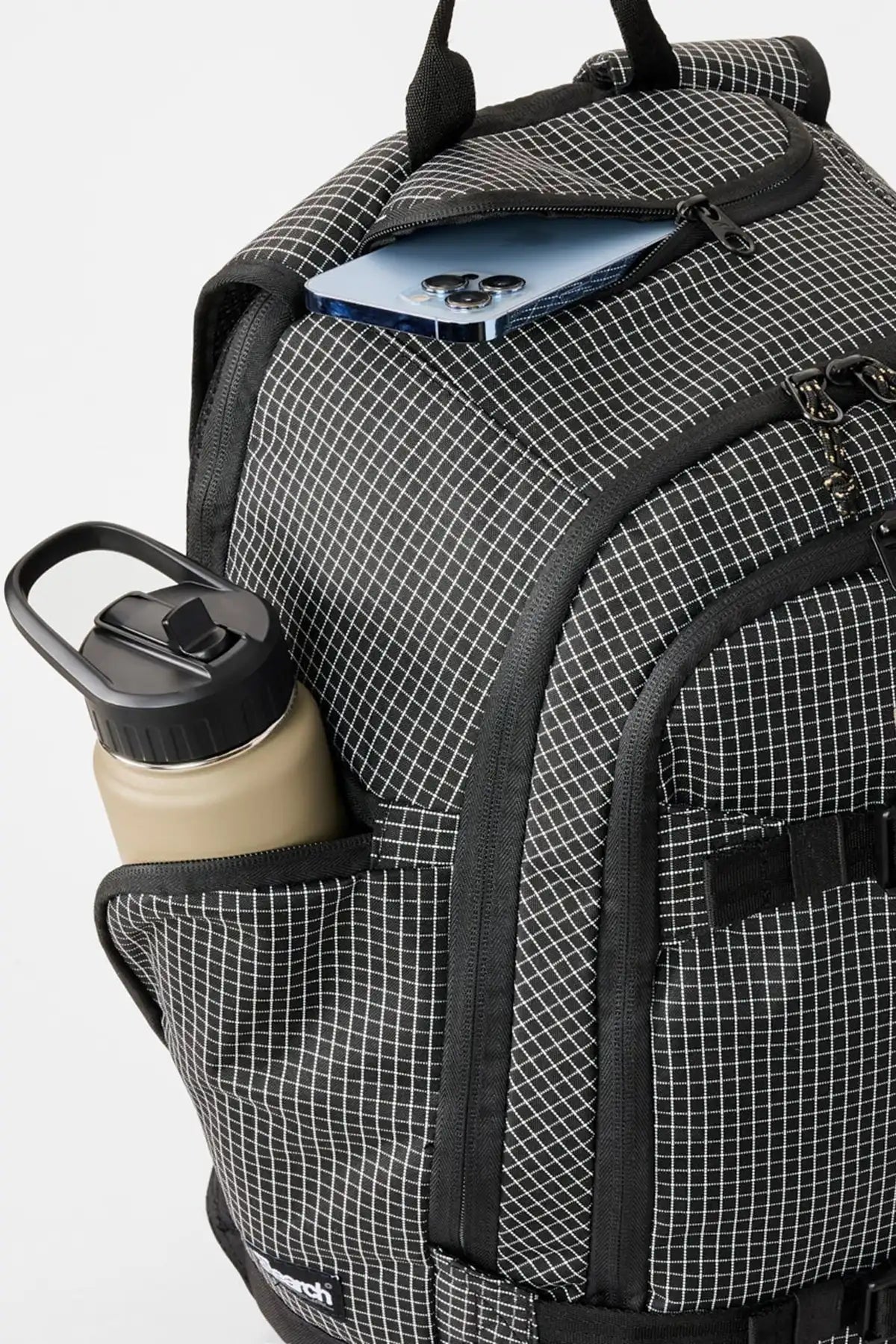 Rip Curl Posse Ripstop 33L black/white checkered backpack with a water bottle and blue item on a light gray background