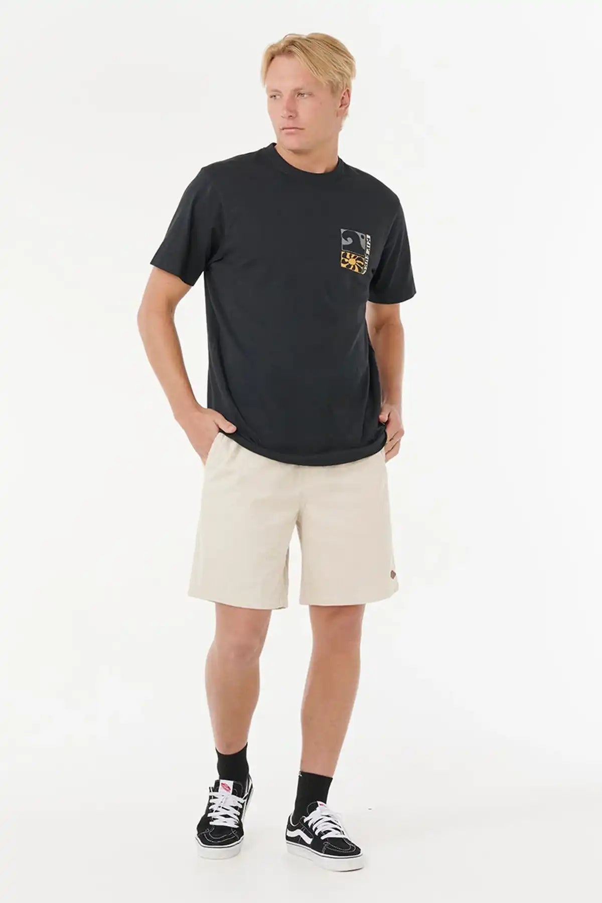 Man wearing a black t-shirt with a Rip Curl logo and beige shorts on a white background