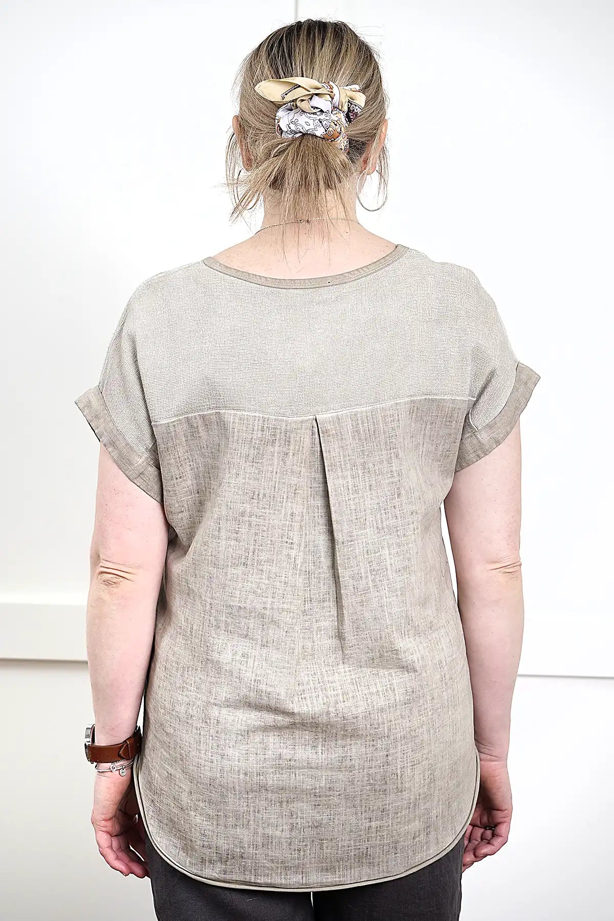 Woman wearing a Rosa V Neck Linen Top in Latte from behind with a plain background