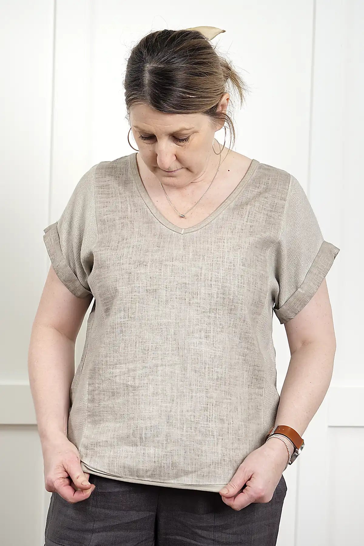 Woman wearing a Rosa V Neck Linen Top in Latte featuring bottom hem against a white background