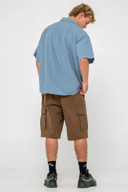 Person wearing a blue shirt and Rusty Commando 23" Baggy Cargo Short in Pinecone, back view against a white background