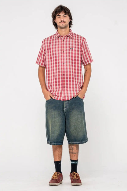Person wearing a Rusty red and white checkered shirt and blue denim shorts on a white background