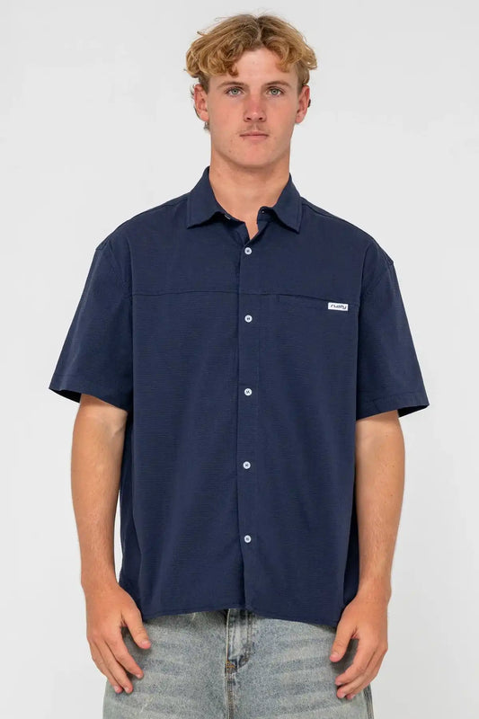 Man wearing a Navy Blue Rusty Giles Short Sleeve Shirt with a brand logo on a white background