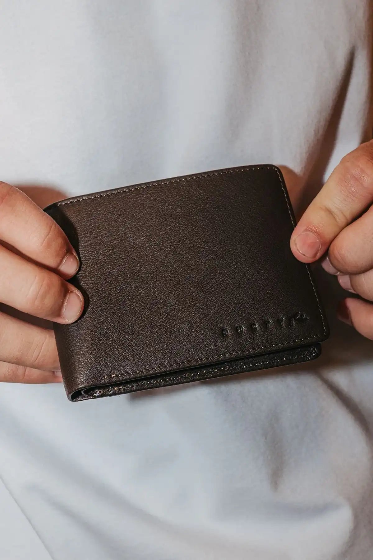 man holding the Rusty High River 2 Leather Coffee Wallet showing the front