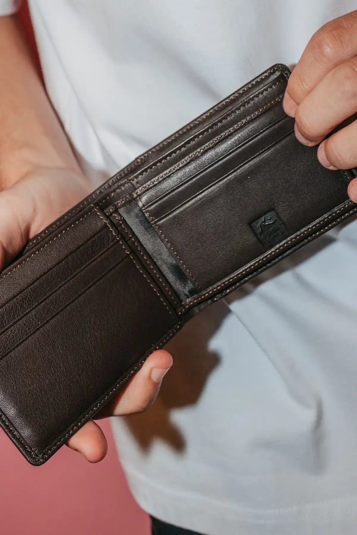man holding the Rusty High River 2 Leather Coffee Wallet open so you can see the carf slots