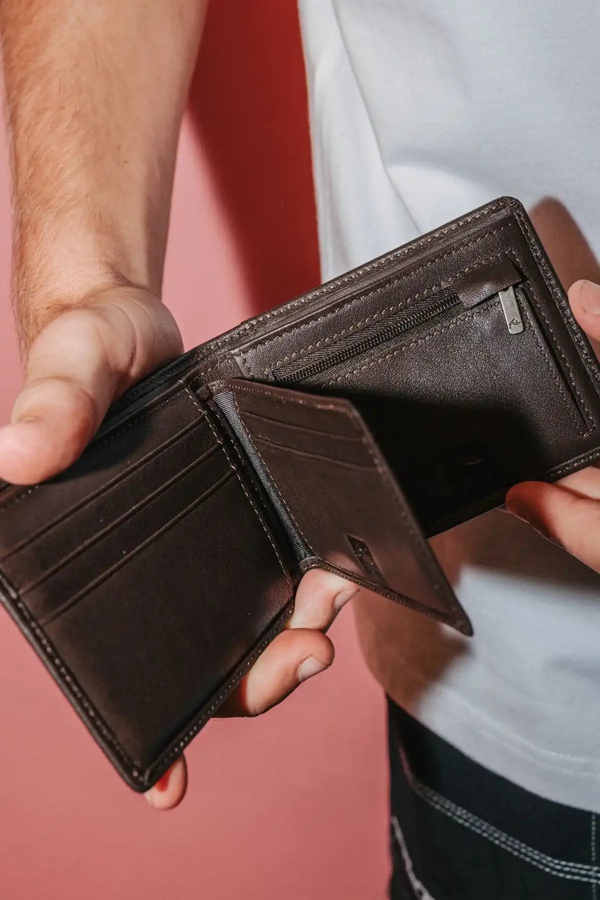 man holding the Rusty High River 2 Leather Coffee Wallet open so you can see the compartments