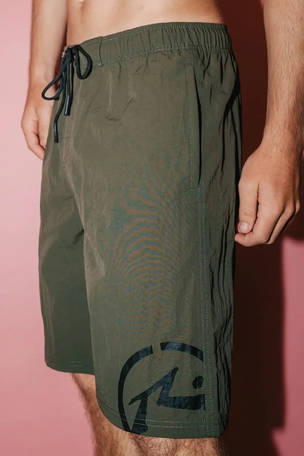 man wearing Rusty Mens BoardShort Peek Show Hybrid Waist in Army Green on white pink background side view