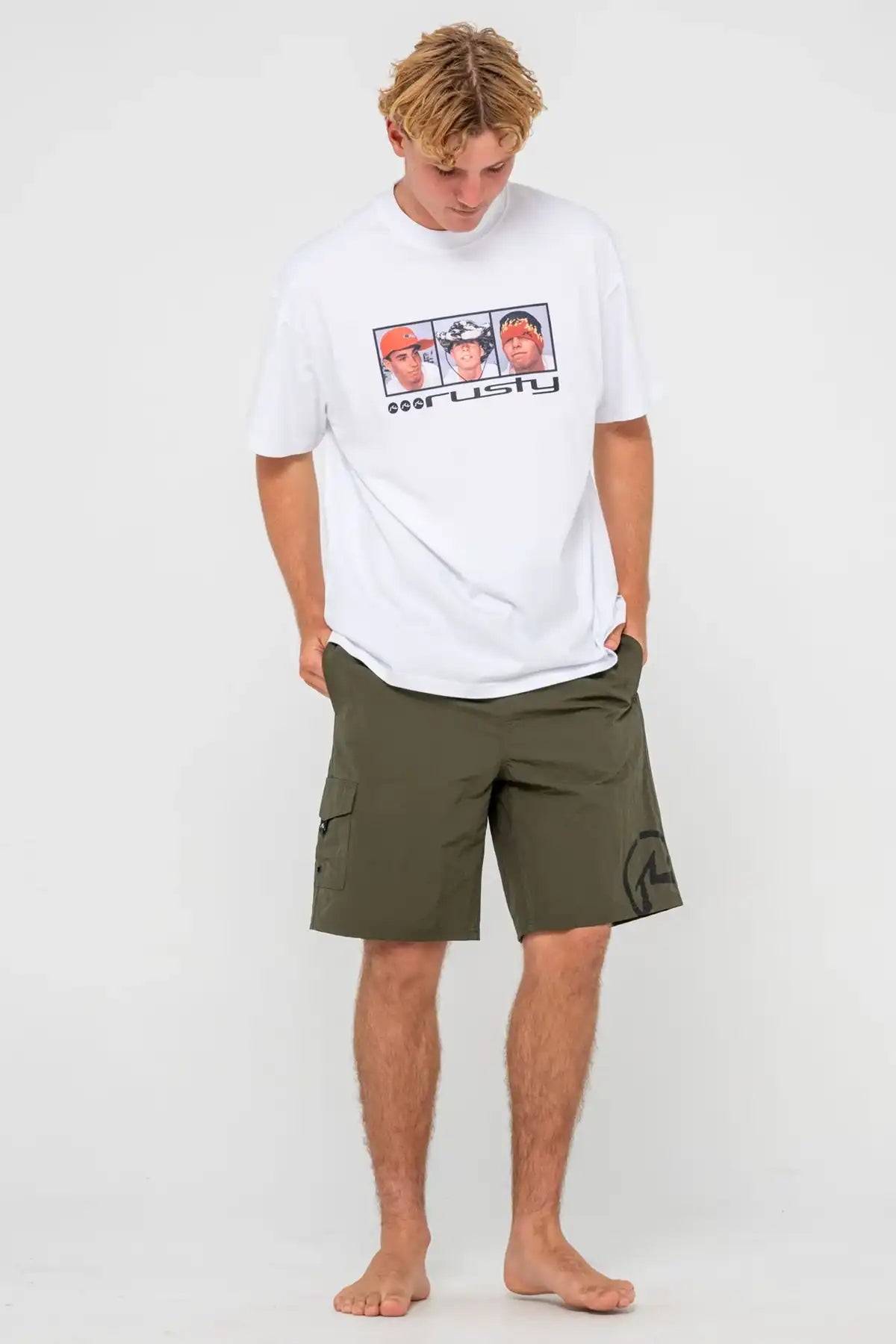 man wearing Rusty Mens BoardShort Peek Show Hybrid Waist in Army Green and a white tee on white background