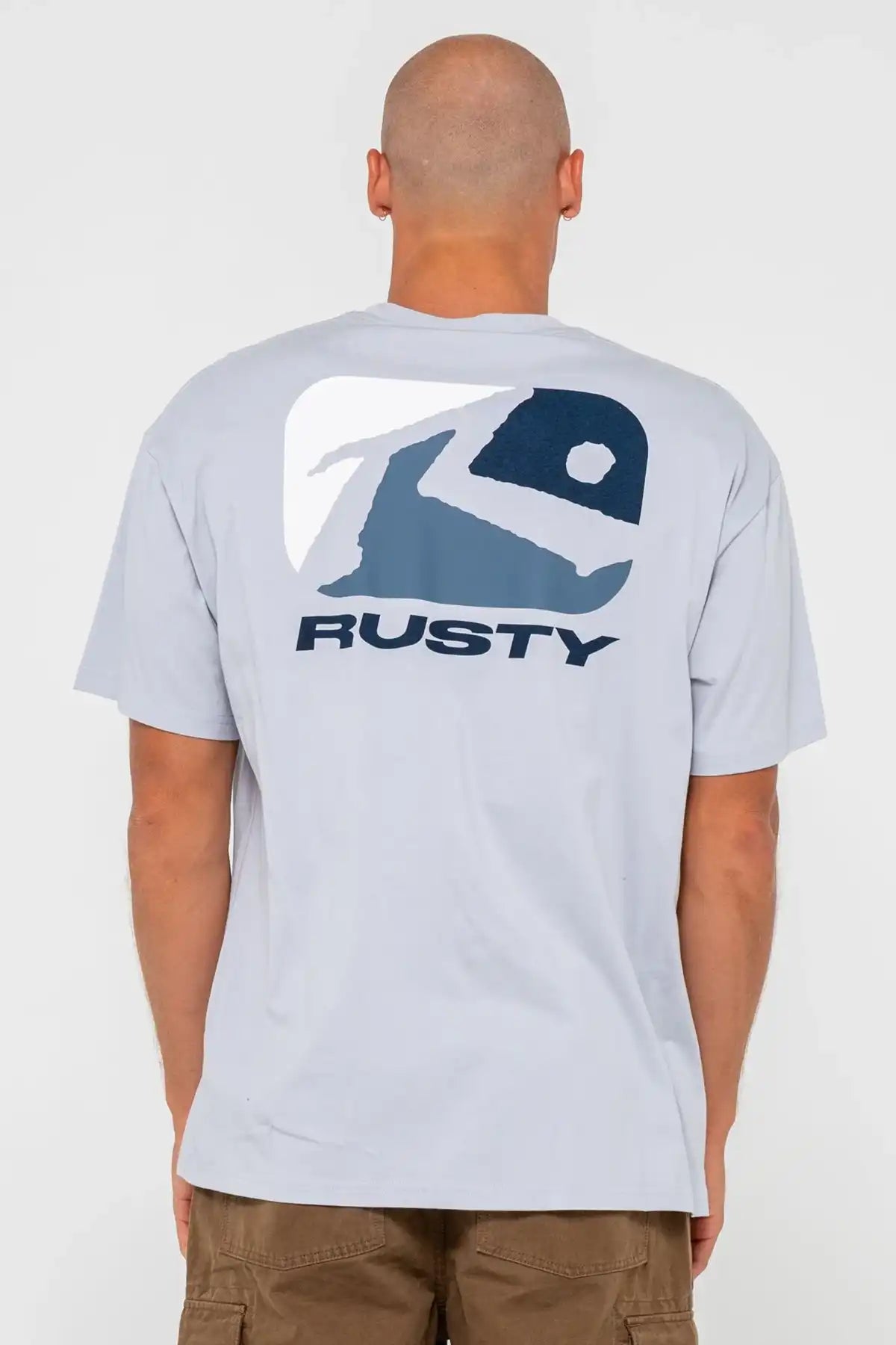 man wearing Rusty Mens Phenom Graphic Tee in Smoke Blue with large logo on the back and pinecone shorts on a white background