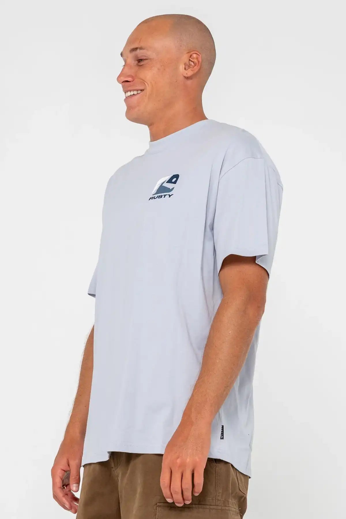 man standing side on wearing a Rusty Mens Phenom Graphic Tee in Smoke Blue and pinecone shorts on a white background