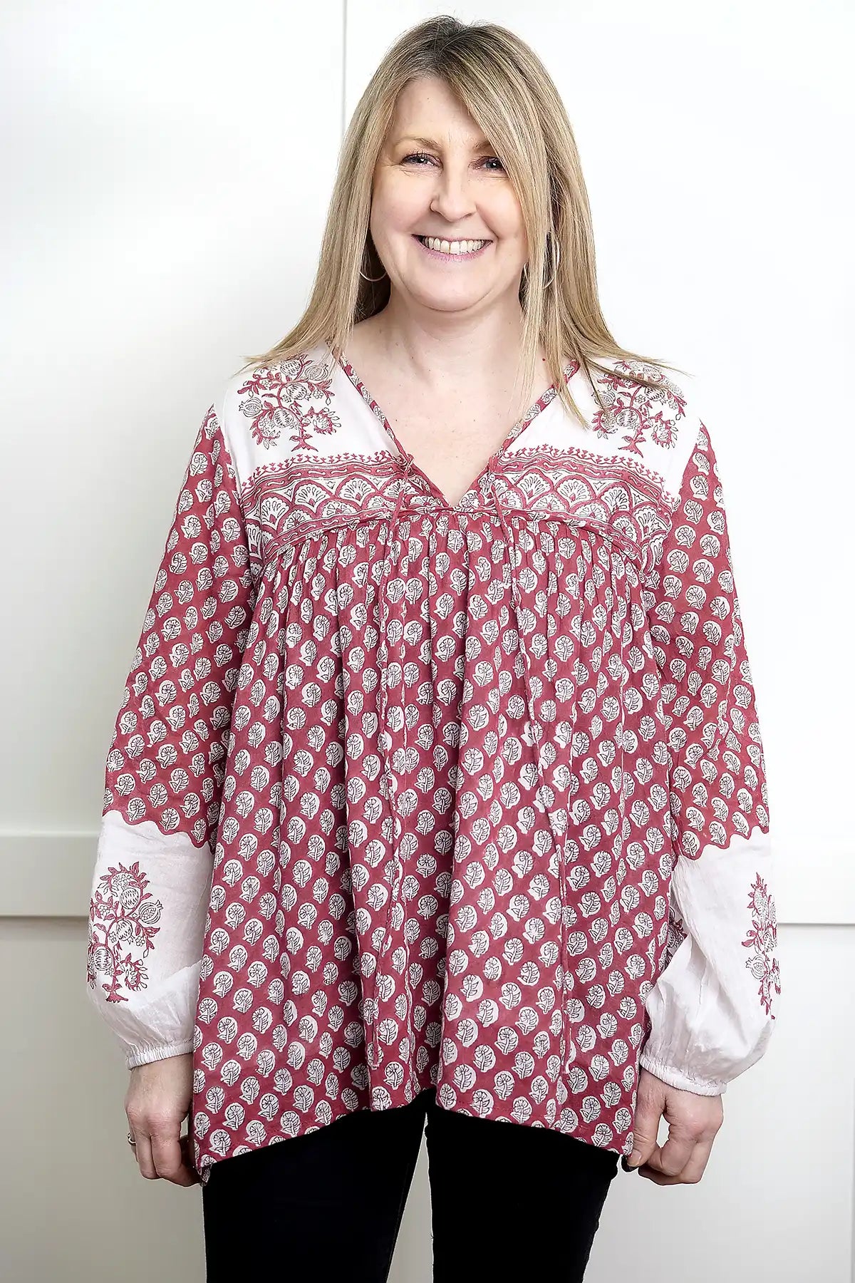 Woman wearing a red and white patterned Seaberry Gypsy Top against a white background - front view