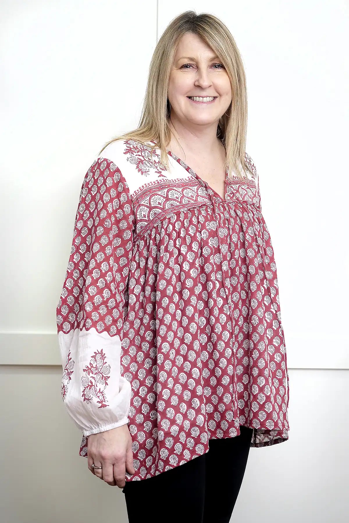 Woman wearing a red and white Seaberry Gypsy Top against a plain background