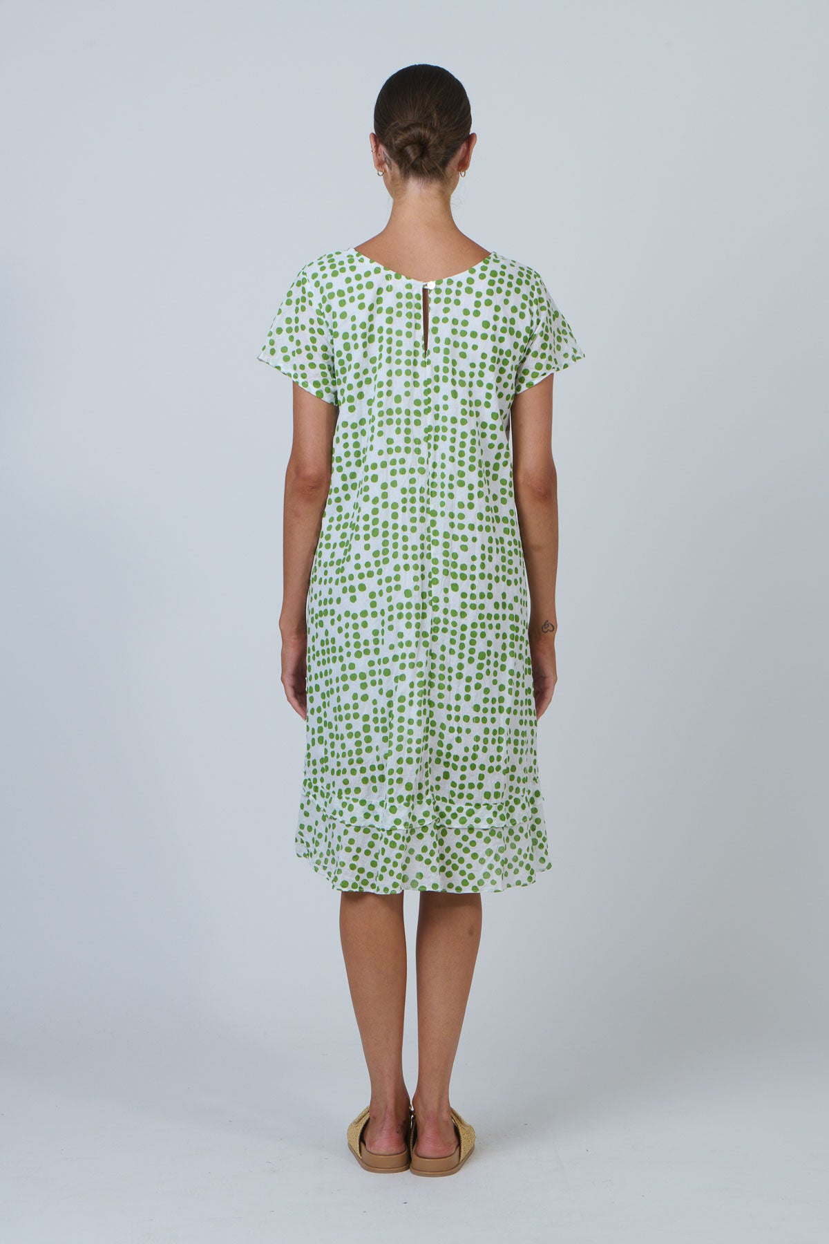 Woman wearing a green patterned dress on a white background