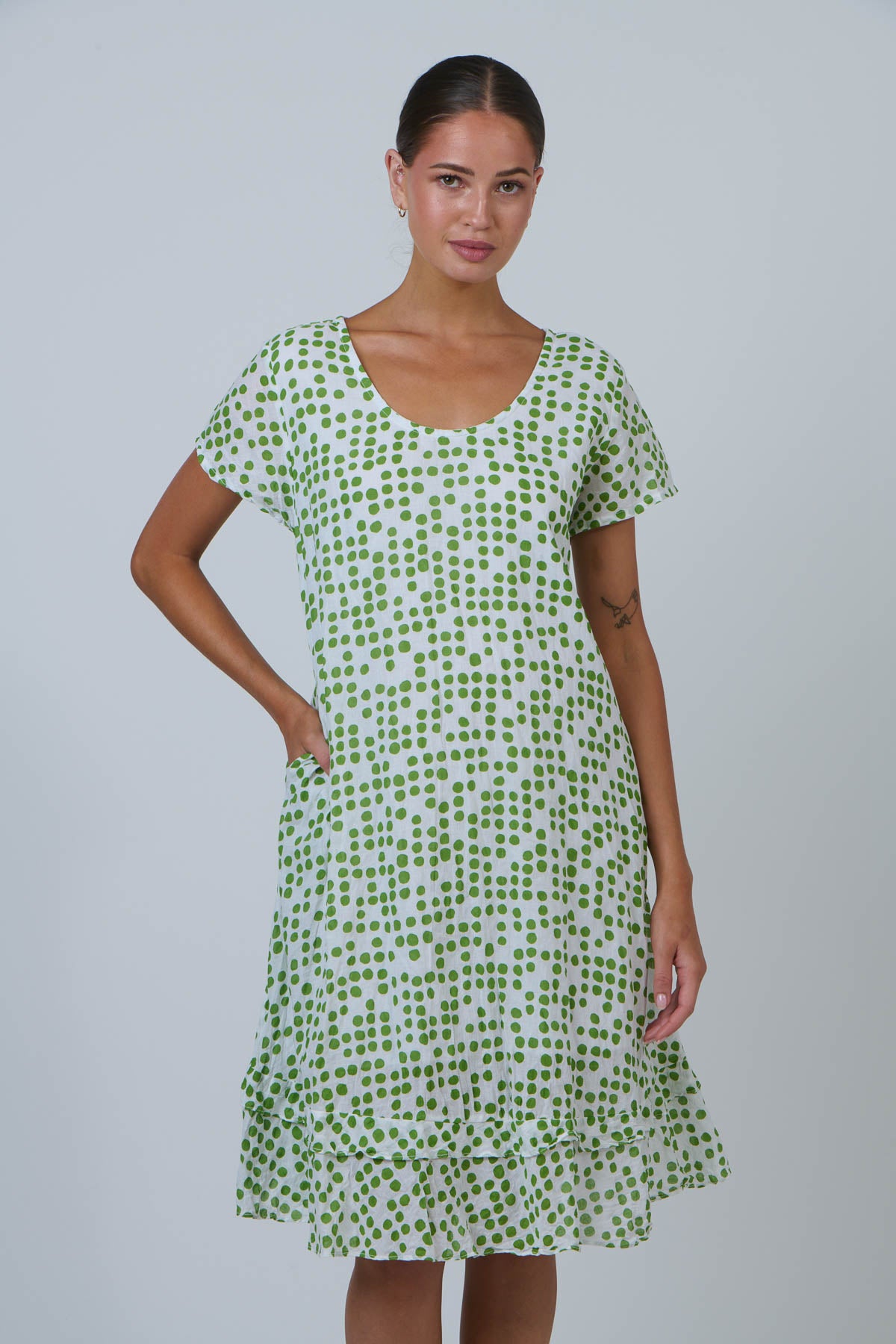 Woman wearing a green patterned dress against a plain background